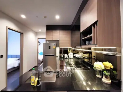 Modern kitchen with sleek black countertops and stainless steel appliances in a stylish apartment.