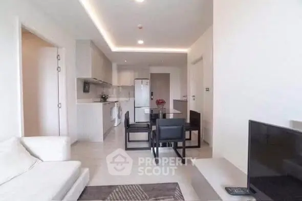 Modern open-plan living room and kitchen with sleek furniture and ambient lighting.