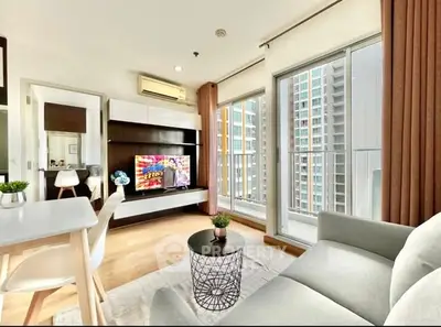 Modern living room with large windows and city view, featuring stylish furniture and decor.