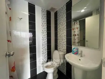 Modern bathroom with stylish black and white tiles and sleek fixtures.