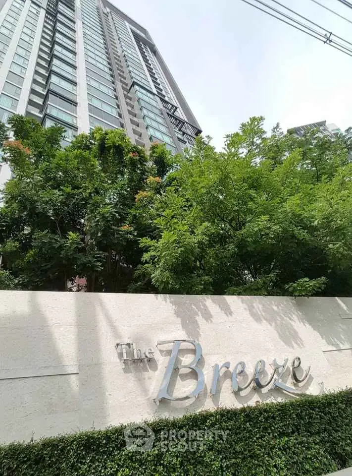 Modern high-rise building with lush greenery and elegant signage.