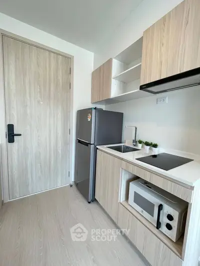 Modern compact kitchen with sleek cabinetry and built-in appliances in a stylish apartment.
