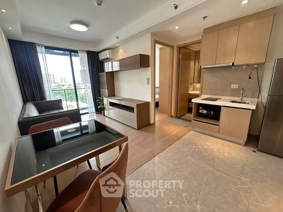 Modern open-plan living room with kitchen, featuring sleek furniture and city view balcony.