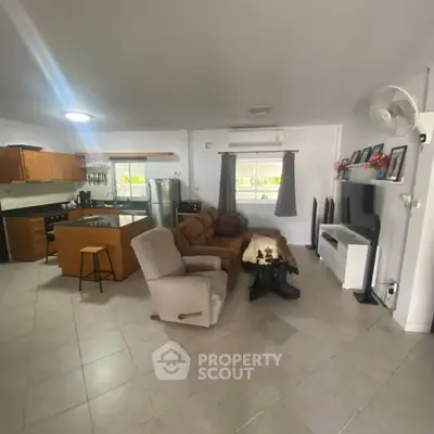 Spacious open-plan living room with modern kitchen and cozy seating area, perfect for family gatherings.
