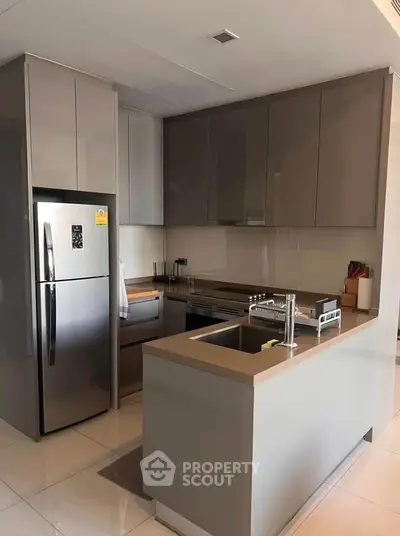 Modern kitchen with sleek cabinetry and stainless steel appliances in a contemporary apartment.