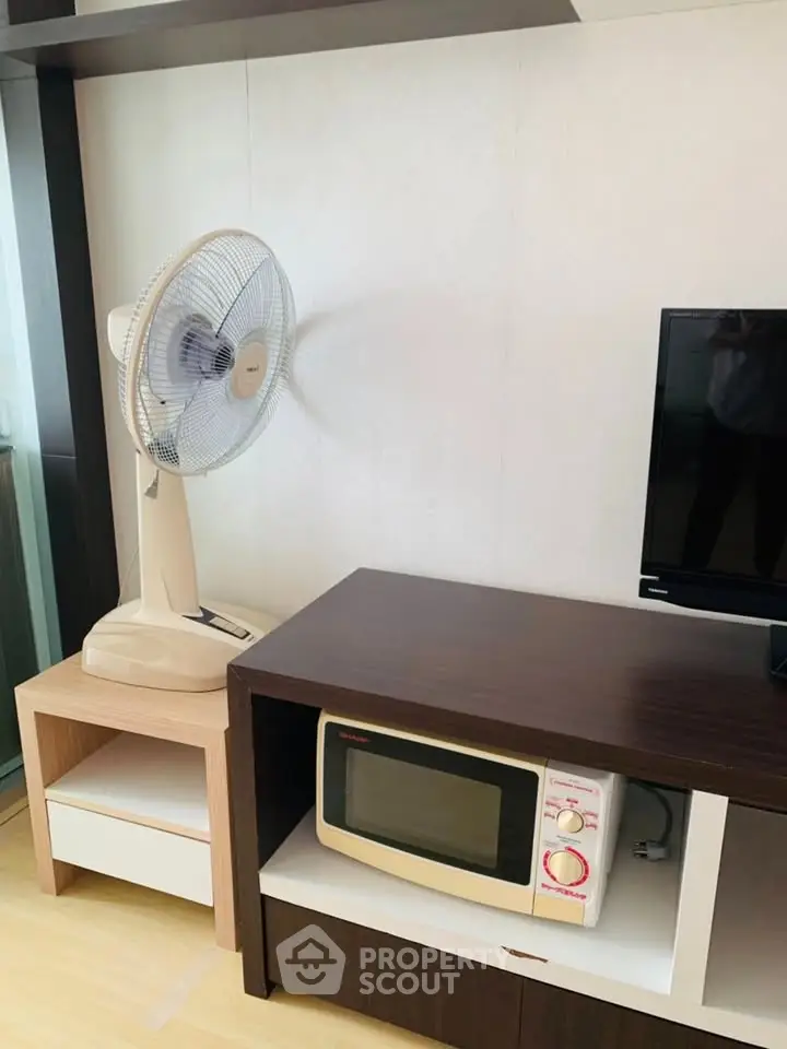 Modern living room with fan, TV, and microwave on stylish wooden furniture.
