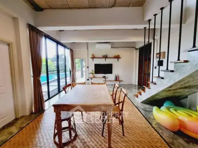 Spacious living room with modern decor, large windows, and pool view, perfect for relaxation and entertainment.