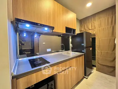 Modern kitchen with sleek wooden cabinets and built-in appliances in a cozy apartment.