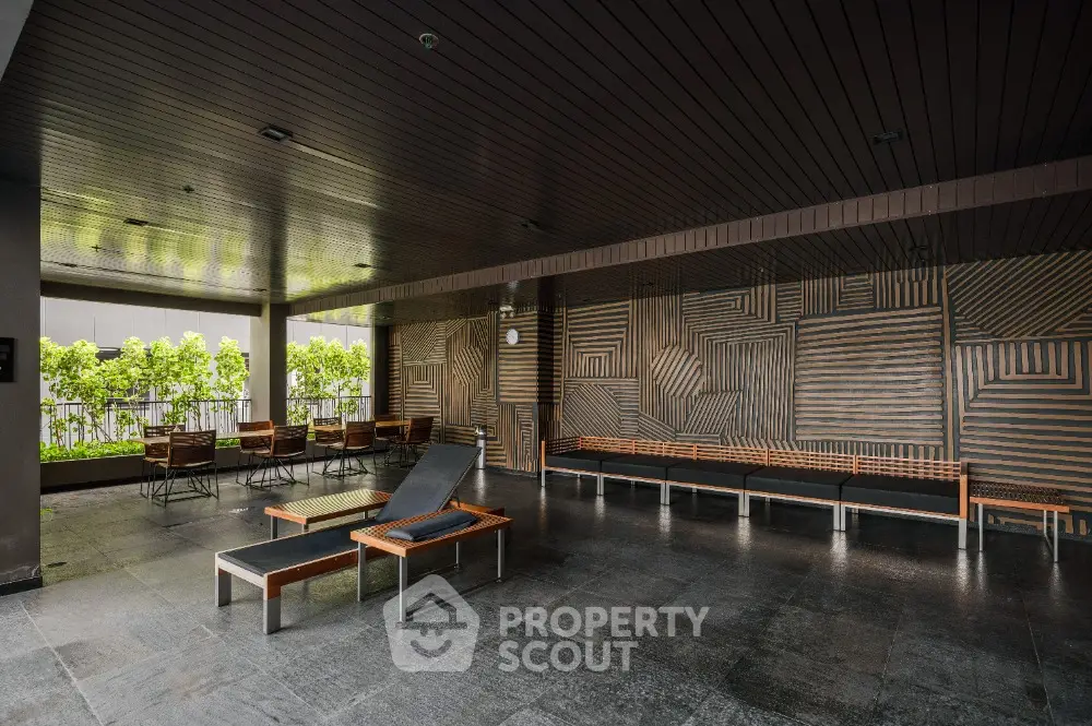 Modern outdoor seating area with stylish wooden furniture and geometric wall design.