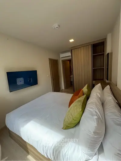 Modern bedroom with stylish decor and wall-mounted TV in a cozy apartment.