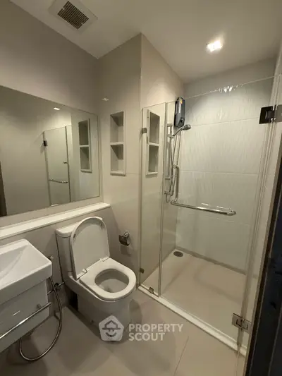 Modern bathroom with glass shower enclosure and sleek fixtures.