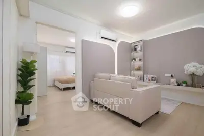 Modern living room with elegant decor and cozy ambiance, featuring a stylish sofa and open access to bedroom.
