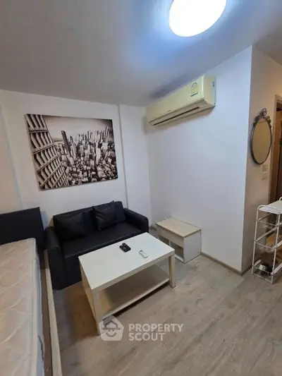 Modern living room with sleek furniture and cityscape artwork, featuring a cozy sofa and air conditioning.