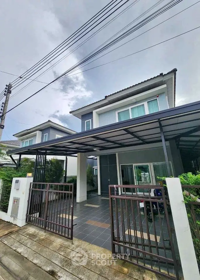 Modern two-story house with gated entrance and covered driveway in suburban neighborhood.