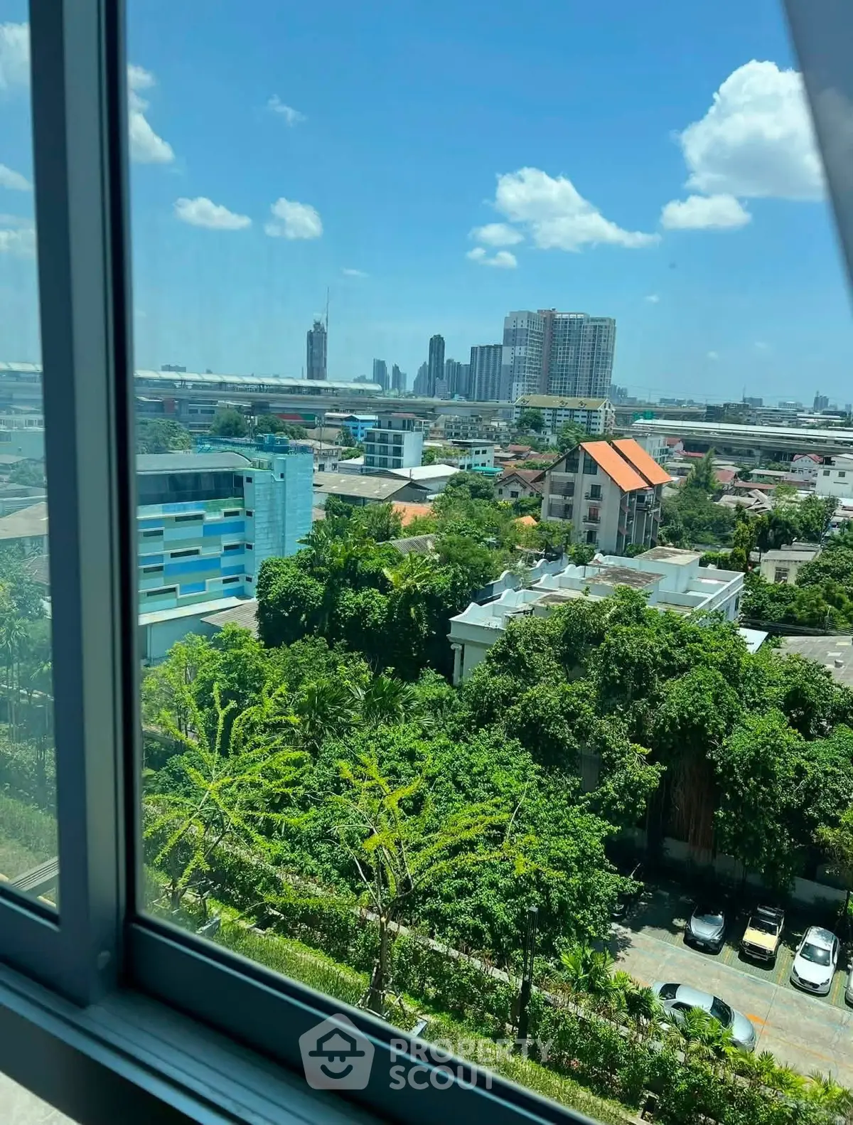 Stunning cityscape view from a high-rise window showcasing lush greenery and urban skyline.