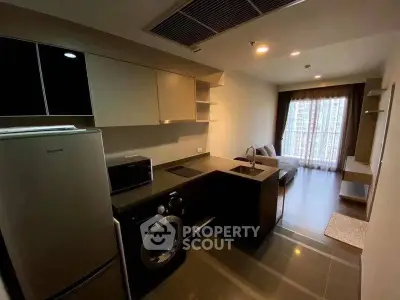 Modern kitchen with sleek appliances and cozy living area in open layout apartment.