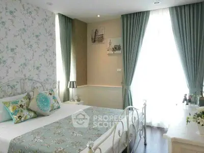Charming bedroom with elegant decor and natural light, featuring stylish curtains and floral accents.