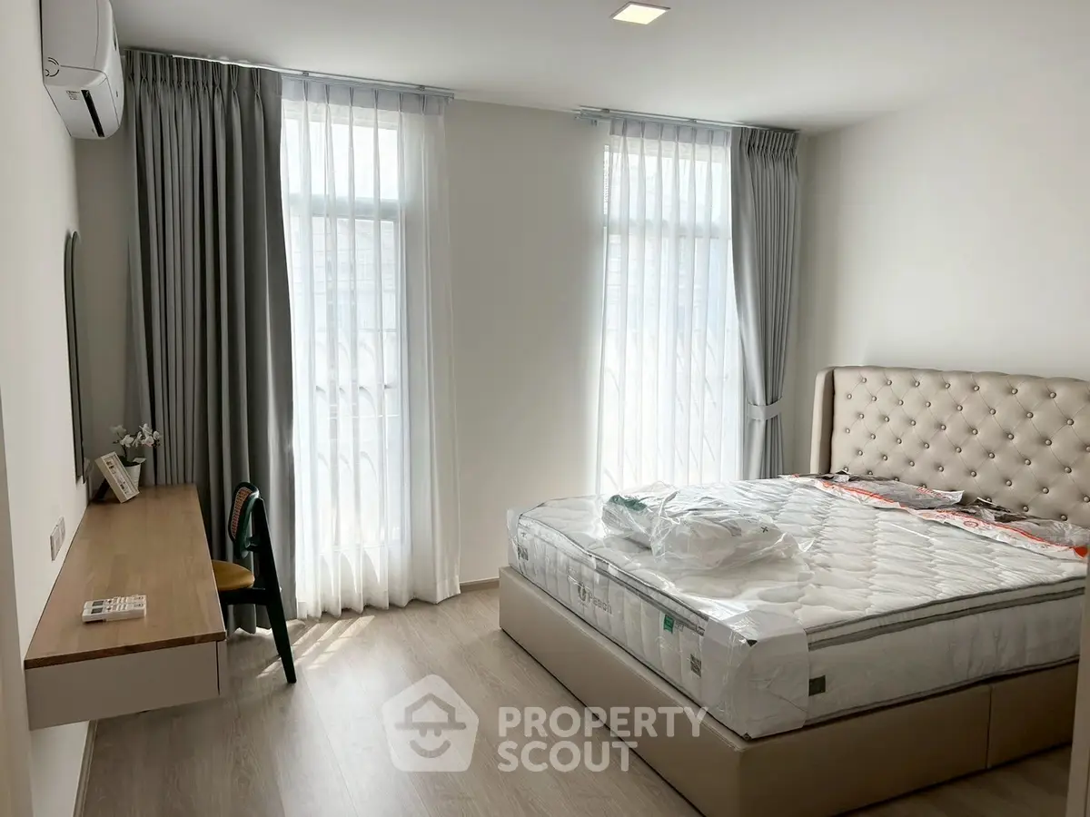 Spacious bedroom with modern decor and natural light in a stylish apartment.