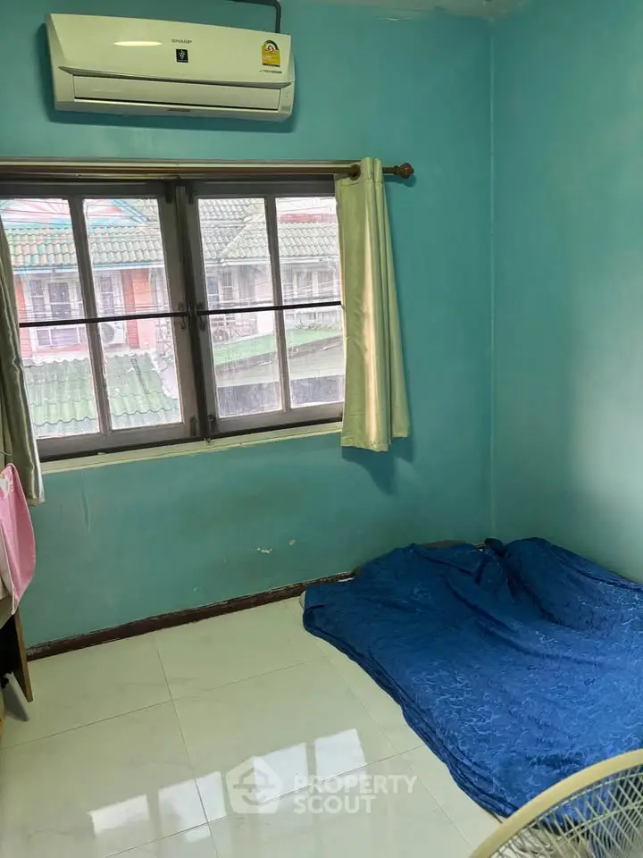 Cozy bedroom with air conditioning and large window offering natural light.