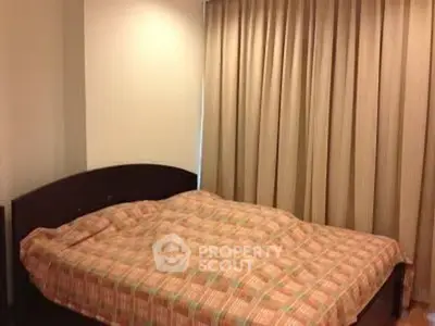 Cozy bedroom with plaid bedding and elegant curtains for a warm, inviting atmosphere.