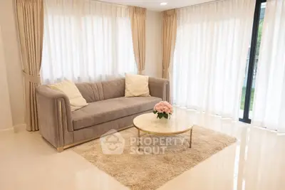 Elegant living room with plush sofa, chic coffee table, and floor-to-ceiling windows with sheer curtains.