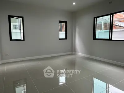 Spacious empty room with large windows and glossy tiled floor in modern home.
