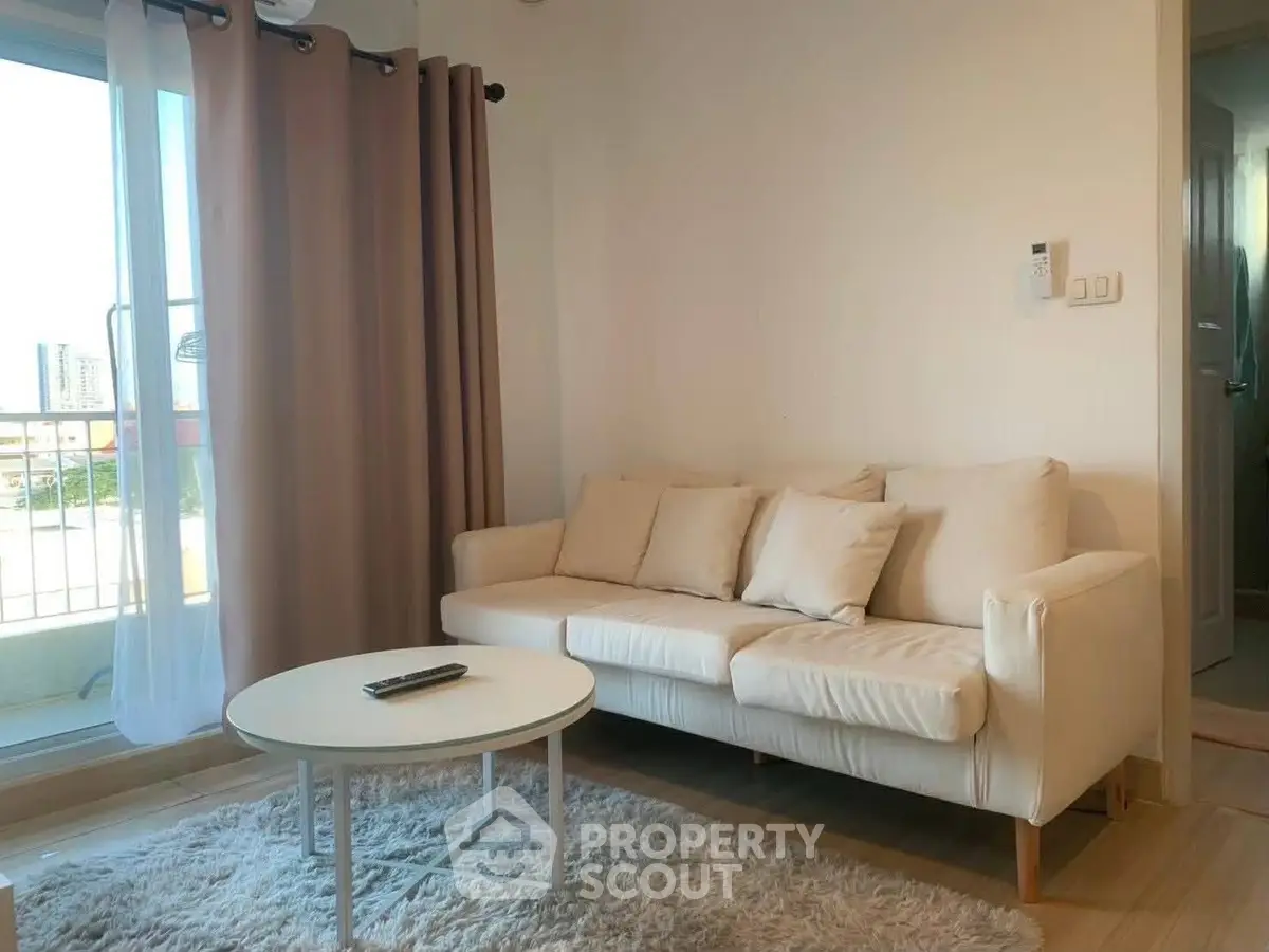 Cozy living room with beige sofa, round coffee table, and balcony view in modern apartment.