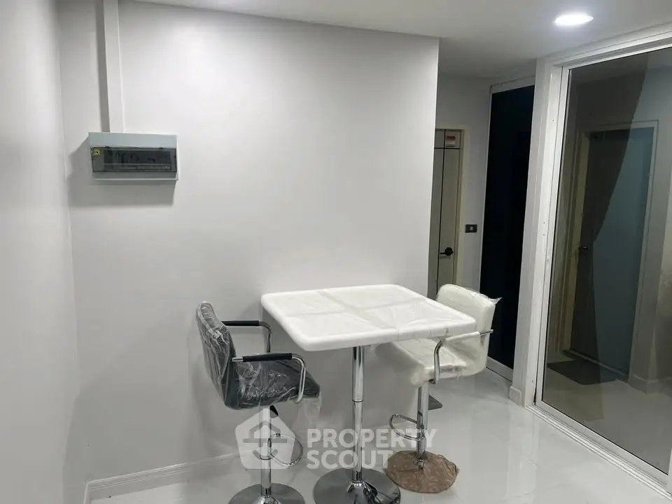 Modern minimalist dining area with sleek white table and stylish chairs in a bright interior space.