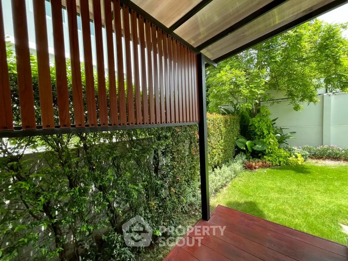 Charming garden view with lush greenery and modern wooden deck, perfect for outdoor relaxation.