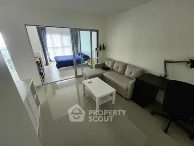 Modern living room with sleek furniture and view into a cozy bedroom.