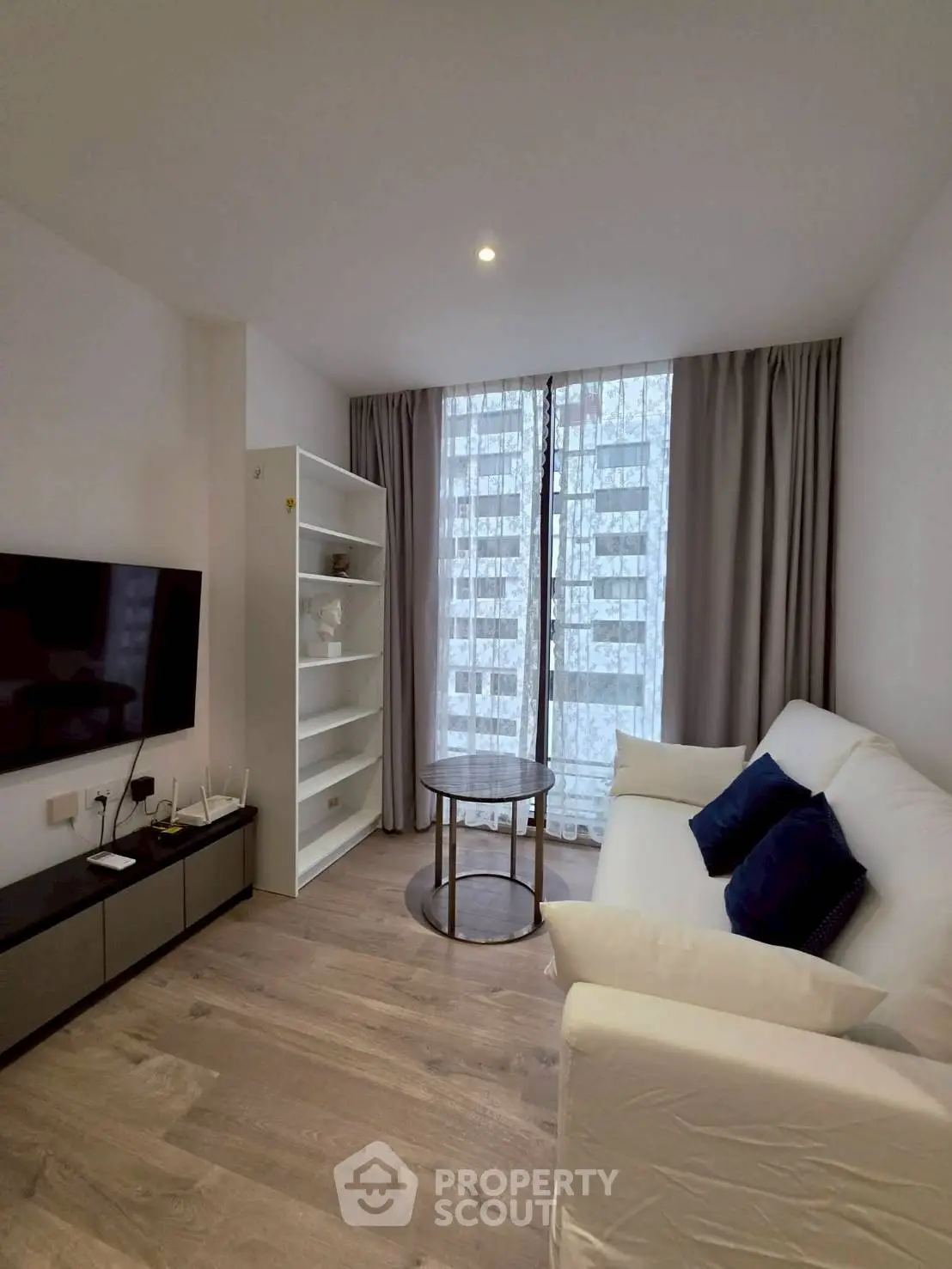 Modern living room with sleek furniture and large window, perfect for urban living.