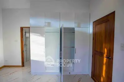 Spacious bedroom with modern white wardrobe and wooden door