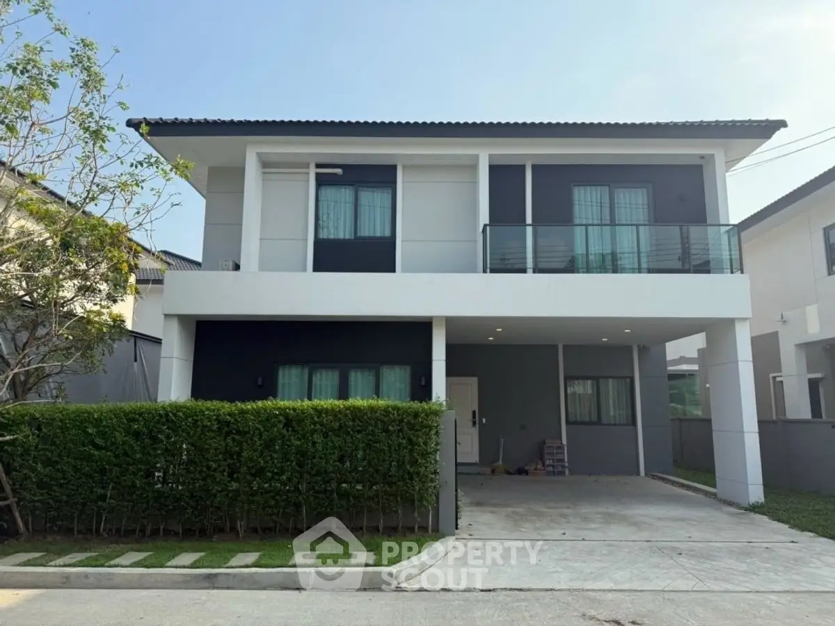 Modern two-story house with sleek design and spacious driveway in a suburban neighborhood.