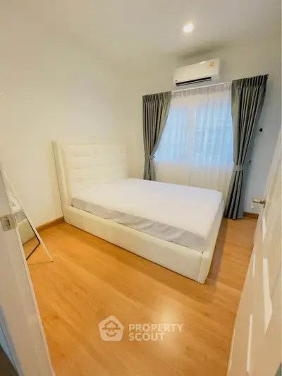 Cozy bedroom with wooden flooring and modern air conditioning unit.