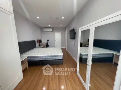 Spacious modern bedroom with mirrored wardrobe and wooden flooring