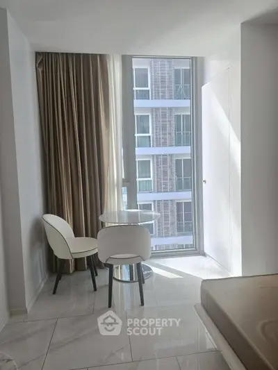 Modern apartment corner with glass table and chairs by a large window