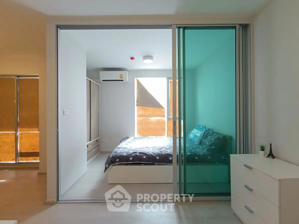 Modern bedroom with sliding glass doors and stylish decor in a contemporary apartment.