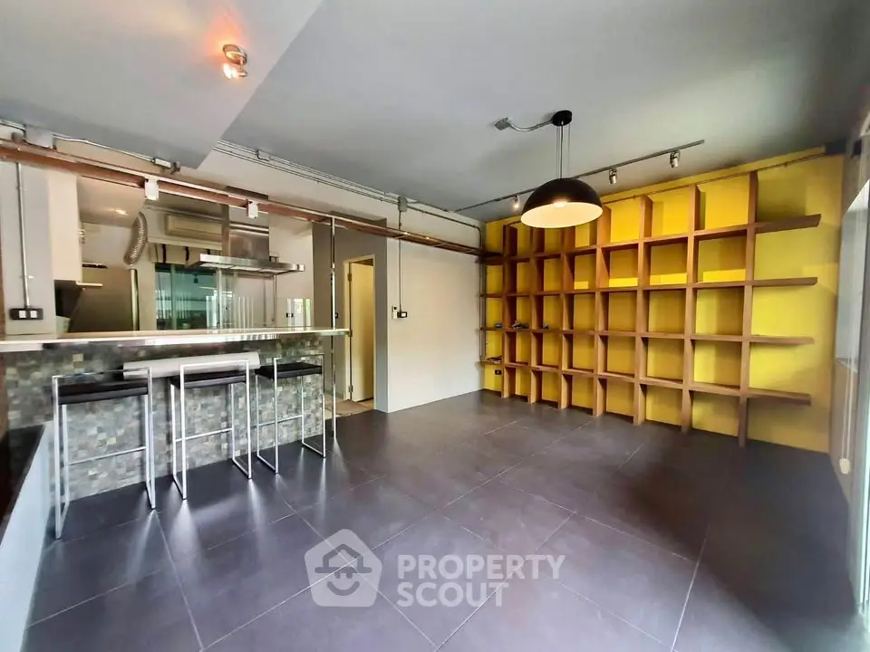 Modern open-plan living room with stylish shelving and breakfast bar in contemporary apartment.