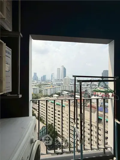 High-rise apartment balcony with stunning city skyline view, featuring laundry area and railing.