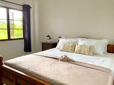 Cozy bedroom with large window and elegant decor, perfect for relaxation.