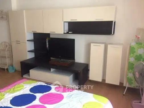 Modern living room with sleek entertainment unit and colorful bedding