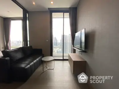 Modern living room with sleek black leather sofa and wall-mounted TV, offering a panoramic city view through floor-to-ceiling windows.