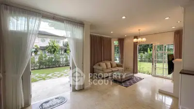 Spacious living room with garden view, elegant decor, and abundant natural light.