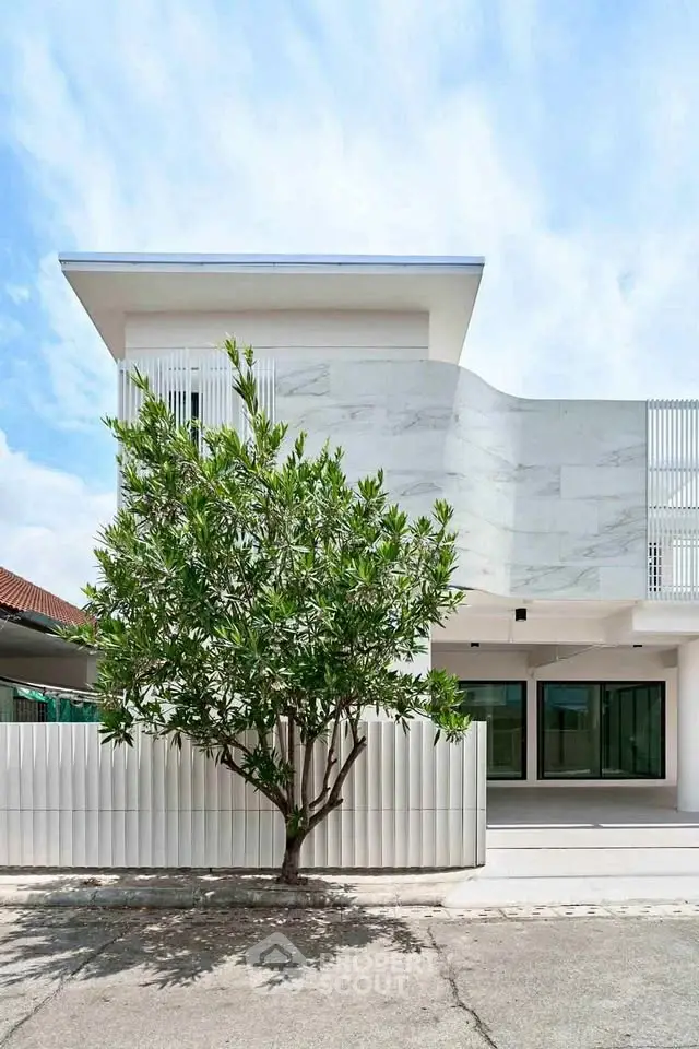 Modern minimalist building exterior with sleek design and lush greenery, perfect for contemporary living.