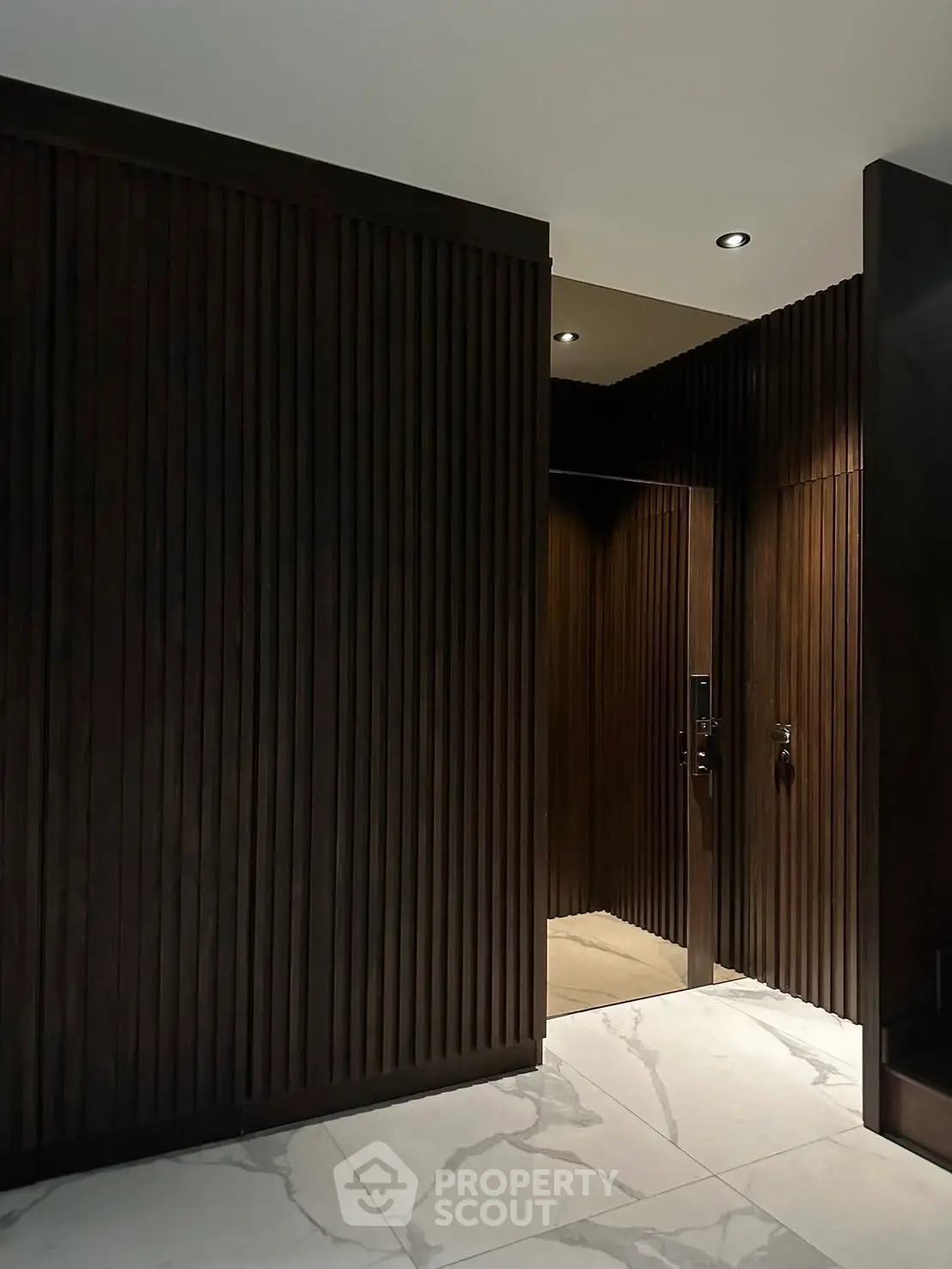 Luxurious modern entrance with sleek wooden paneling and elegant marble flooring.