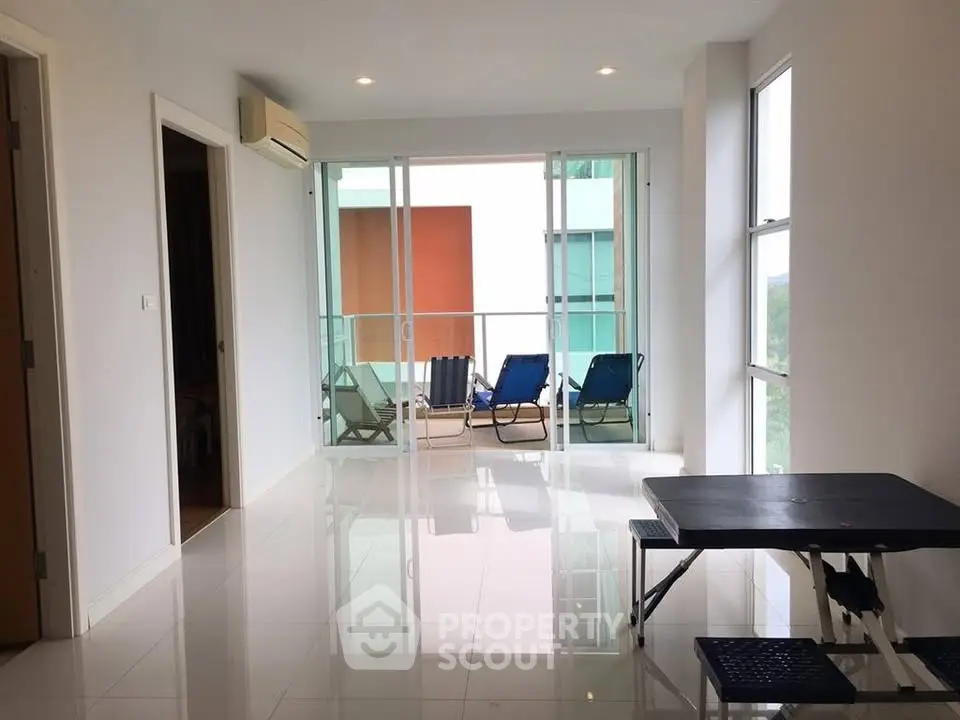 Spacious living room with large windows and balcony access, perfect for natural light and relaxation.