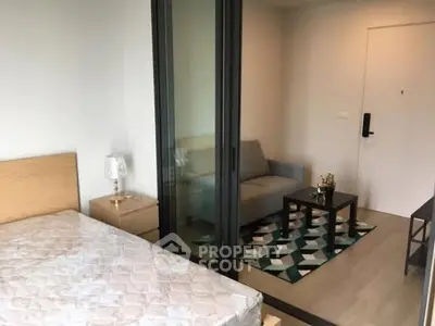 Modern studio apartment with cozy living area and bedroom separated by glass doors.