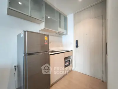 Modern compact kitchen with sleek cabinetry and stainless steel fridge