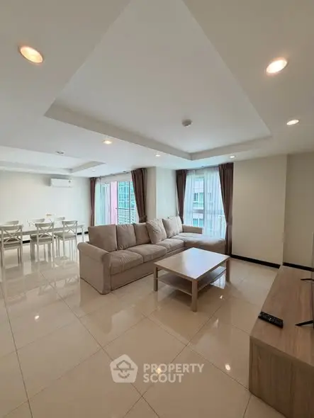 Spacious modern living room with large windows and elegant furnishings in a high-rise apartment.