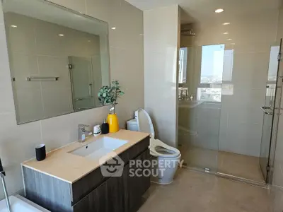 Modern bathroom with sleek fixtures and large mirror in a high-rise apartment.